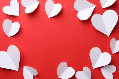 Photo of Frame of white paper hearts on red background, flat lay. Space for text