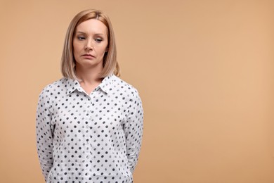 Portrait of sad woman on beige background. Space for text