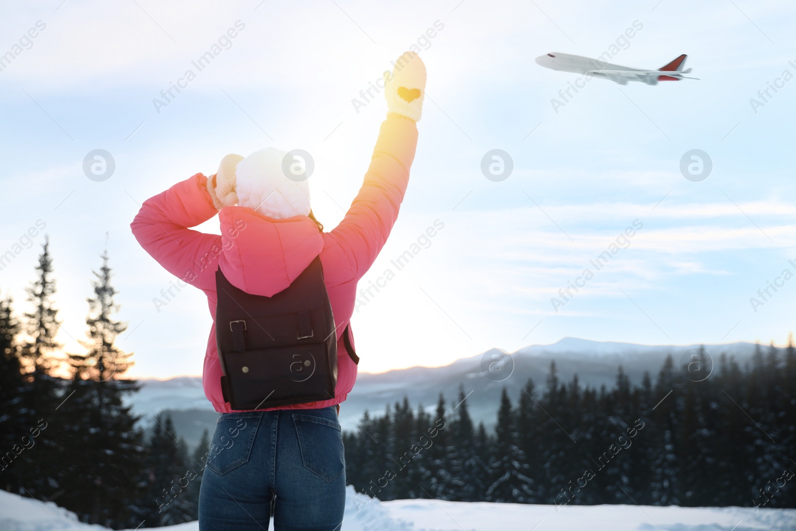 Image of Young woman waving to airplane outdoors. Winter vacation