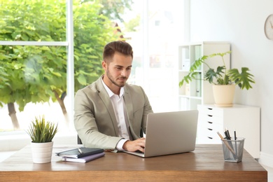 Photo of Man in office wear using laptop at table indoors