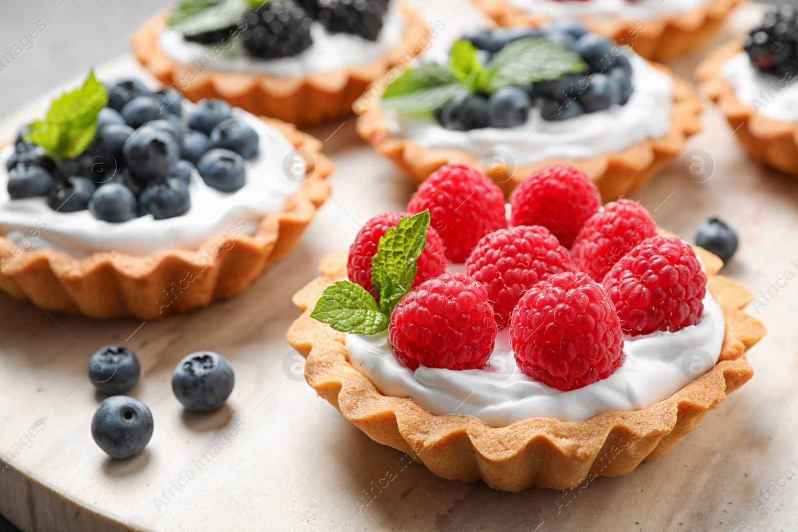 Photo of Different berry tarts on table, closeup. Delicious pastries