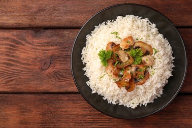 Photo of Delicious rice with mushrooms and parsley on wooden table, top view. Space for text