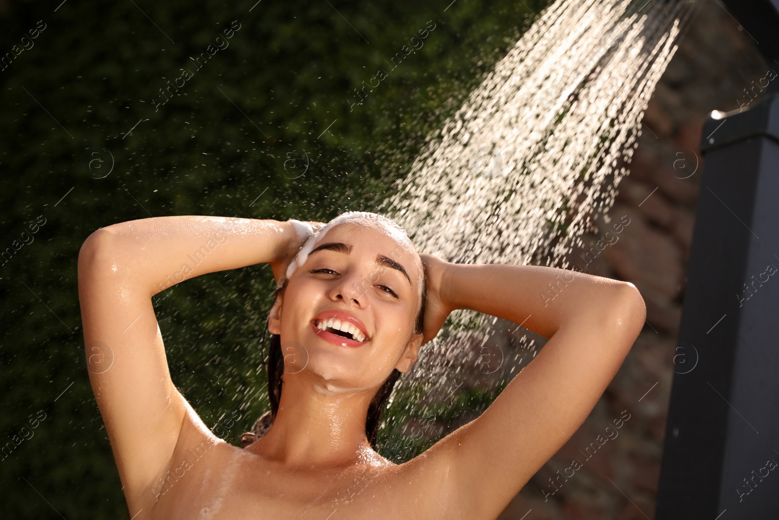 Photo of Woman washing hair in outdoor shower on summer day