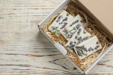 Box with scented sachets on white wooden table, top view. Space for text