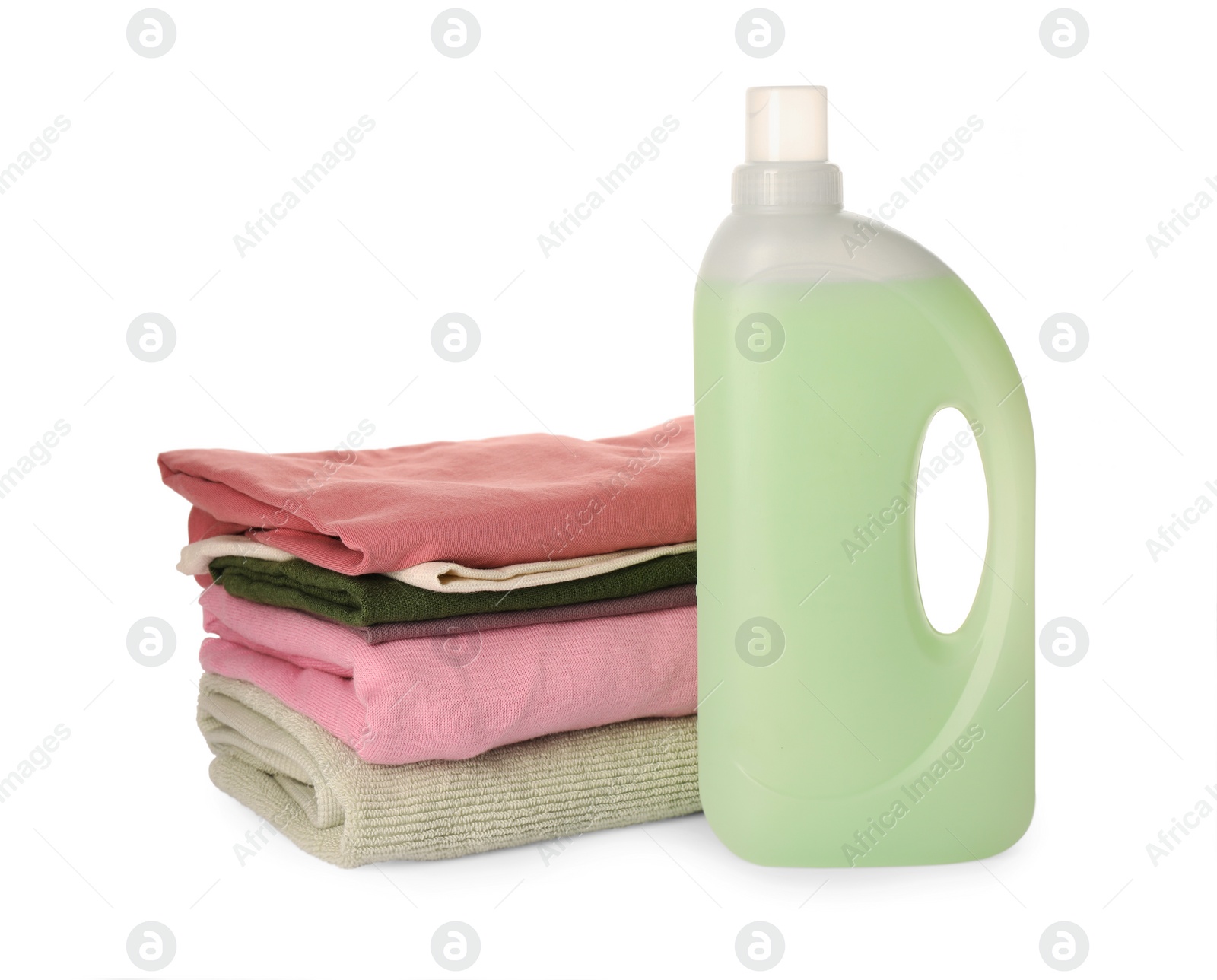 Photo of Bottle of fabric softener and stacked clean clothes isolated on white