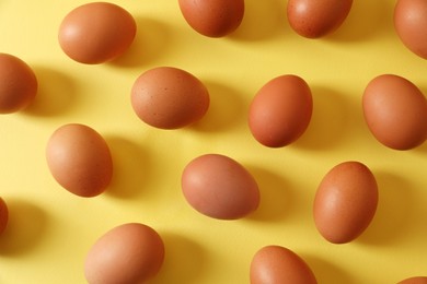Photo of Fresh chicken eggs on yellow background, flat lay