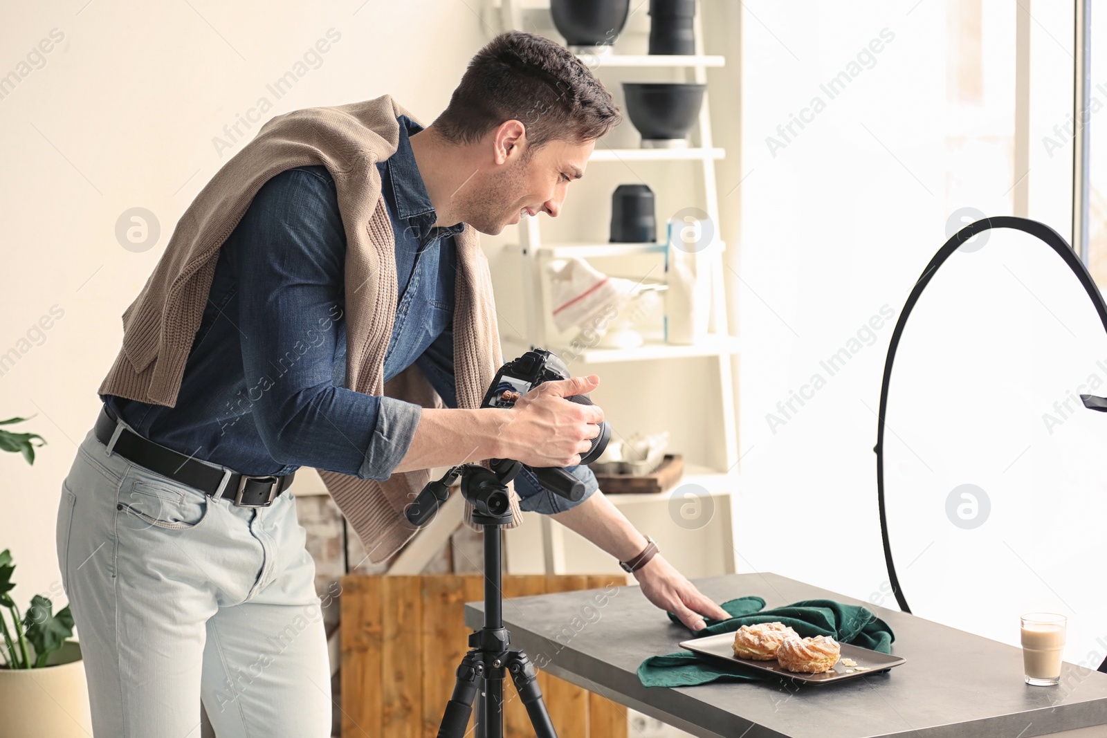 Photo of Young man with professional camera preparing food composition in photo studio