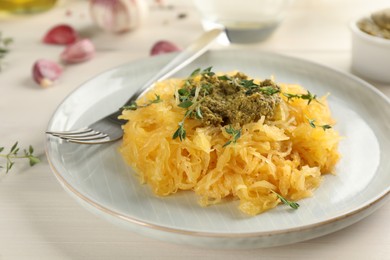 Photo of Tasty spaghetti squash with pesto sauce and thyme served on white wooden table