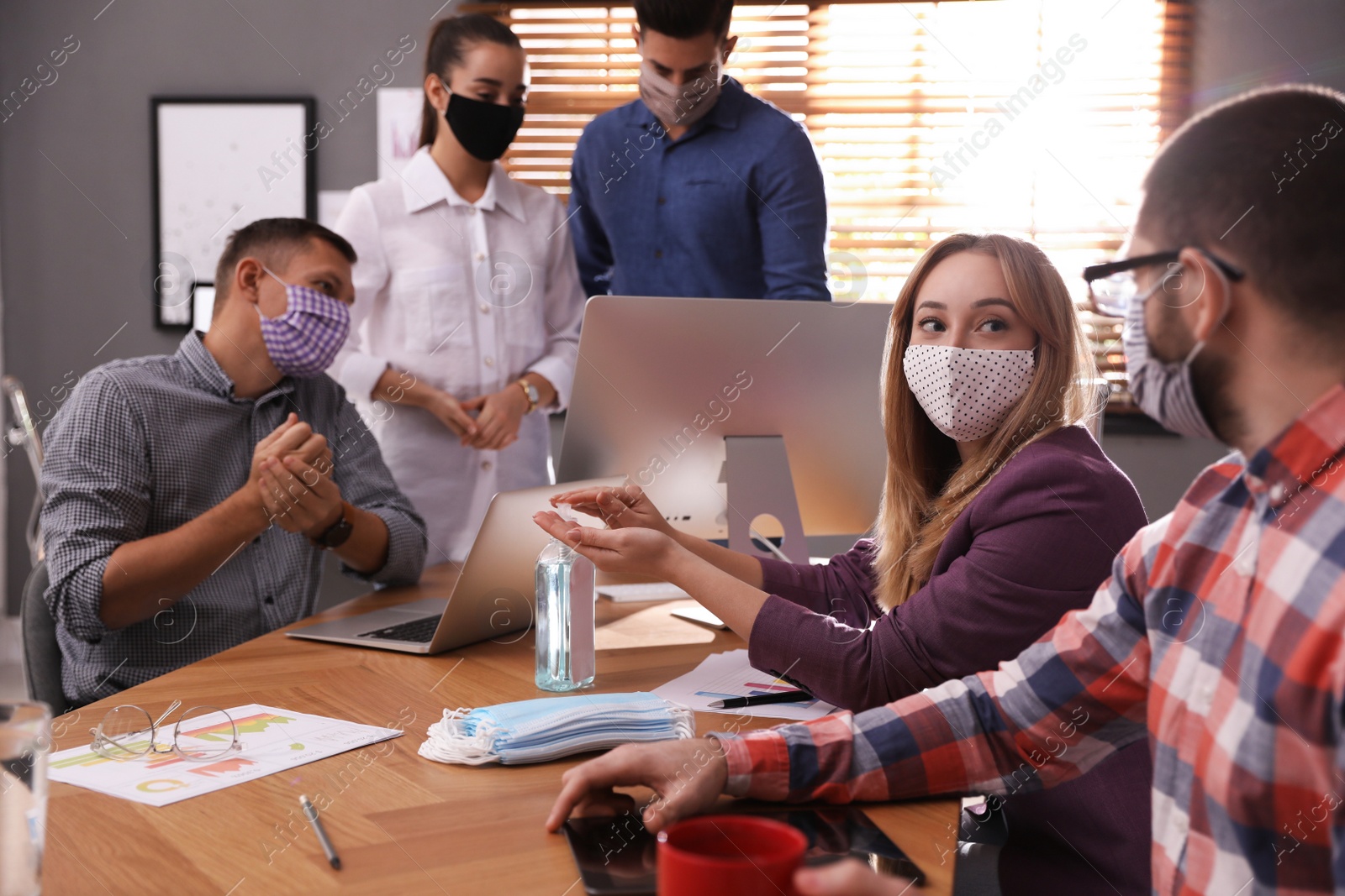 Photo of Group of coworkers with protective masks in office. Business meeting during COVID-19 pandemic