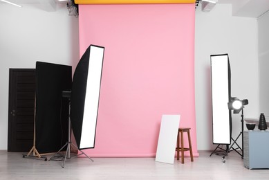 Pink photo background, stool and professional lighting equipment in studio