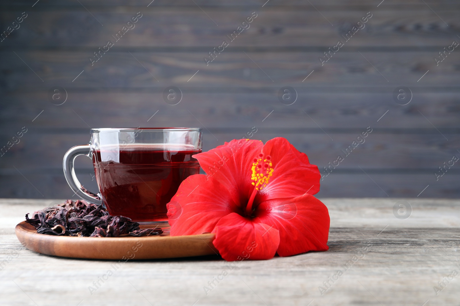 Photo of Delicious hibiscus tea and flowers on wooden table. Space for text