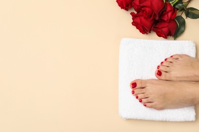 Photo of Woman with stylish red toenails after pedicure procedure and rose flowers on beige background, top view. Space for text