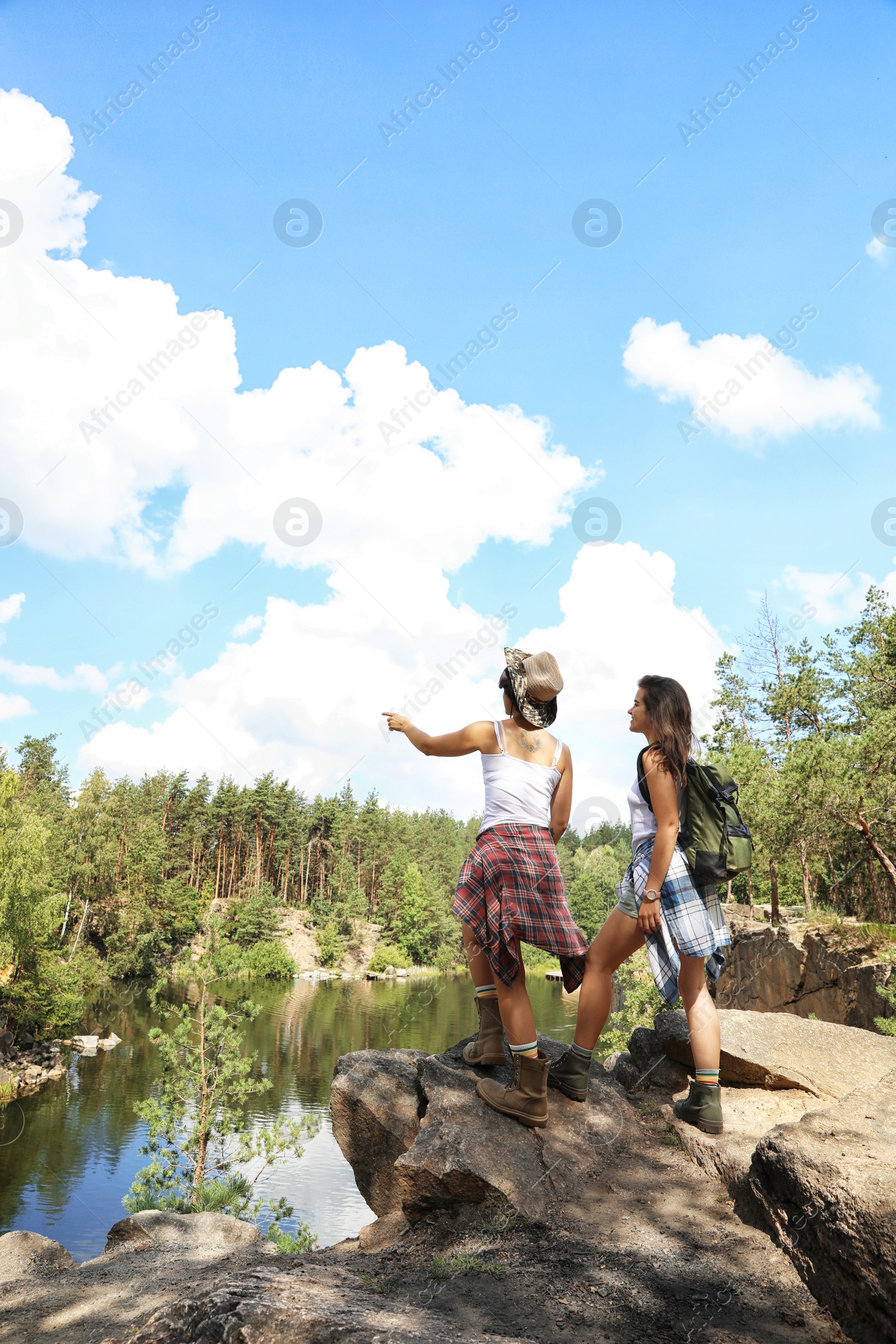 Photo of Young friends on rocky mountain in forest. Camping season