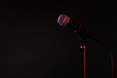 Photo of Modern microphone on stand against black background. Space for text