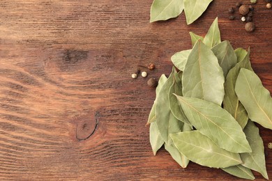 Aromatic bay leaves and spices on wooden table, flat lay. Space for text