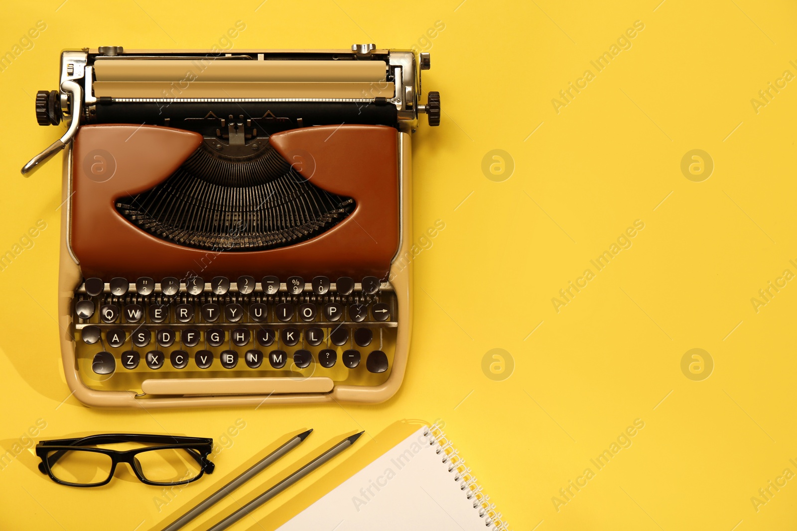 Photo of Vintage typewriter, glasses and stationery on yellow background, flat lay. Space for text