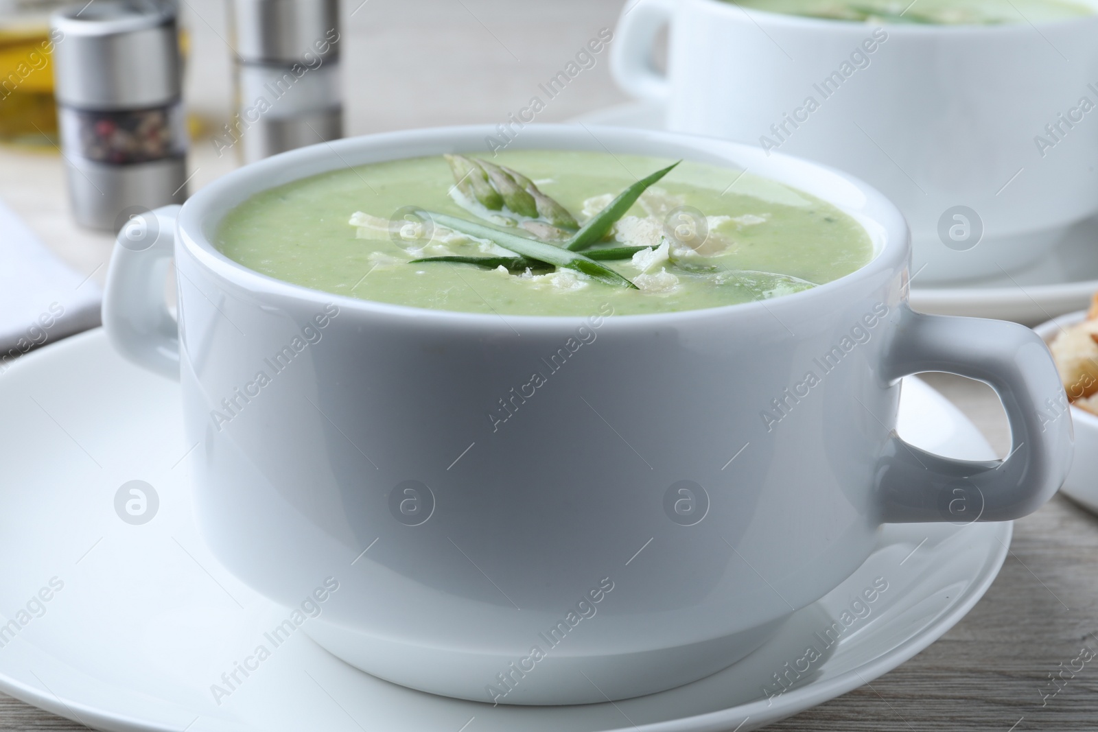 Photo of Delicious asparagus soup with green onion on white table, closeup