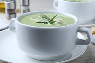 Delicious asparagus soup with green onion on white table, closeup