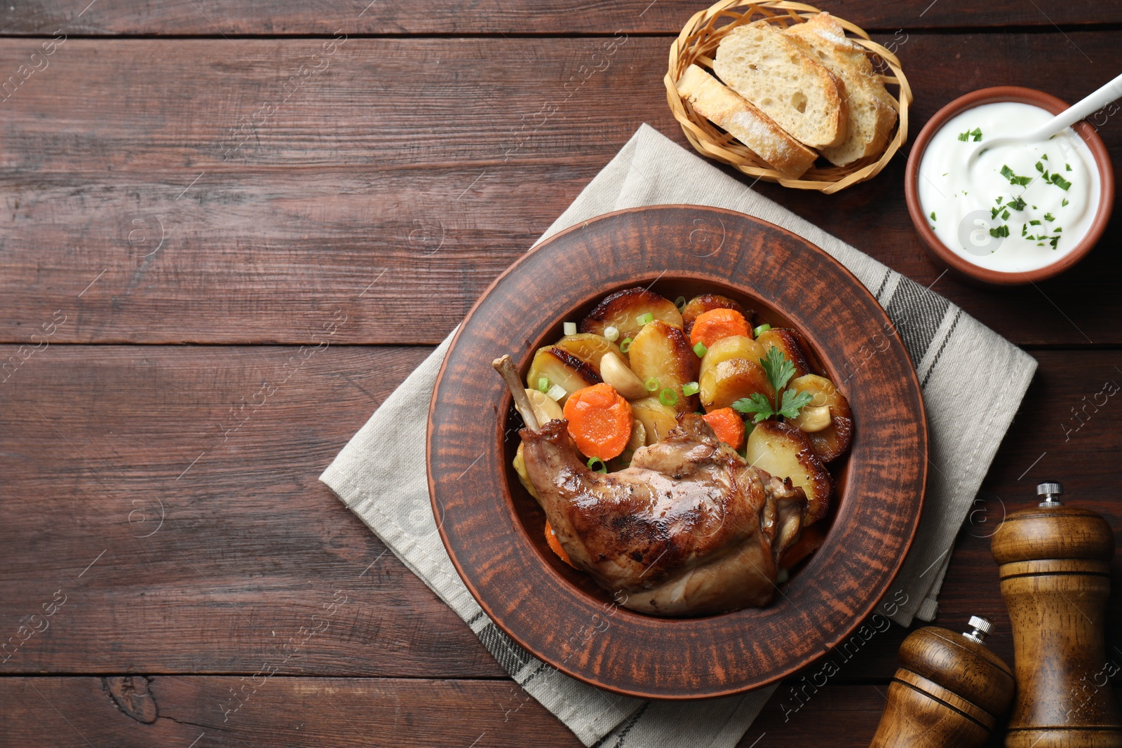 Photo of Tasty cooked rabbit meat with vegetables served on wooden table, flat lay. Space for text