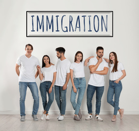 Immigration concept. Group of young people standing near light wall