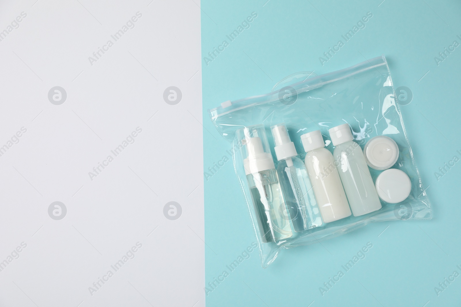 Photo of Cosmetic travel kit in plastic bag on color background, top view and space for text. Bath accessories