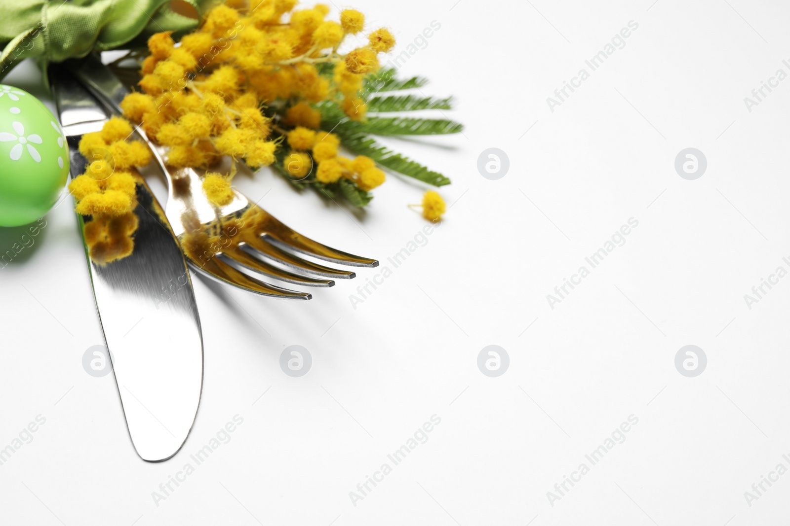 Photo of Cutlery set with floral decor for Easter celebration on white background, closeup