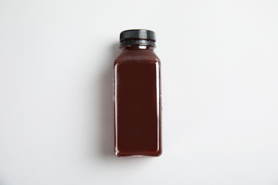 Photo of One bottle with tasty drink on color background, top view