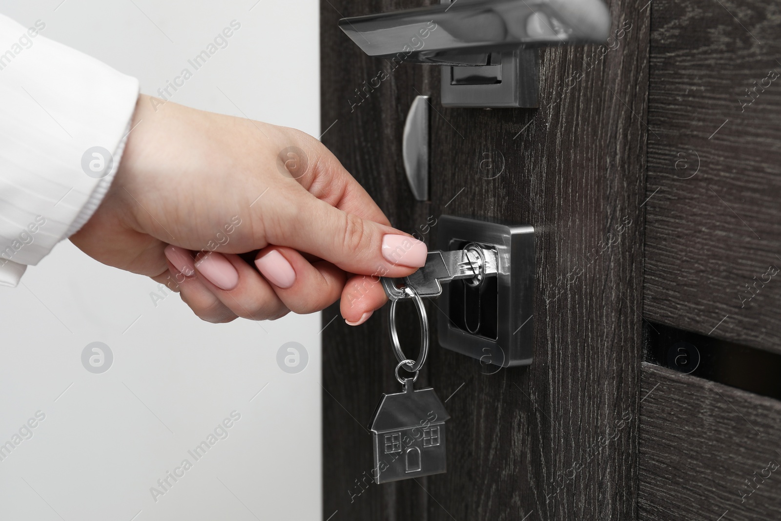 Photo of Woman unlocking door with key, closeup view