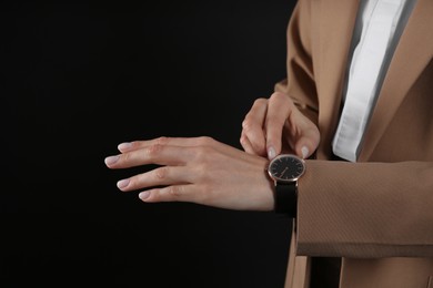 Photo of Businesswoman with wristwatch on black background, closeup. Time management