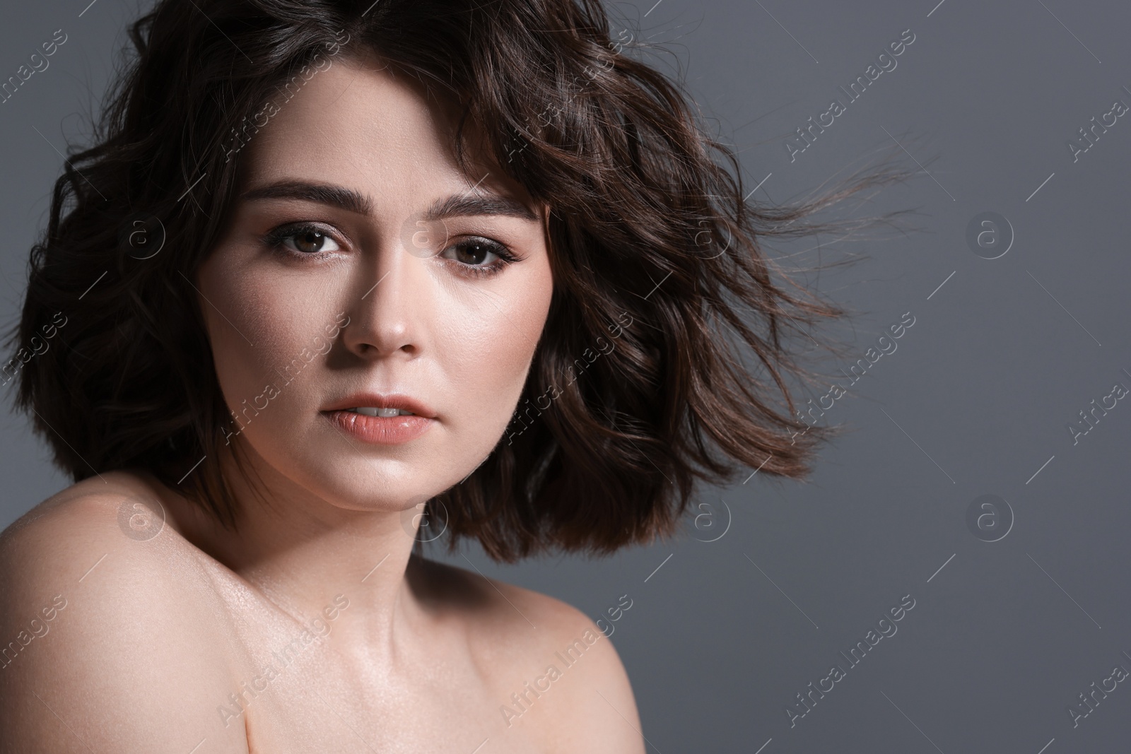 Photo of Portrait of beautiful young woman with wavy hairstyle on grey background. Space for text