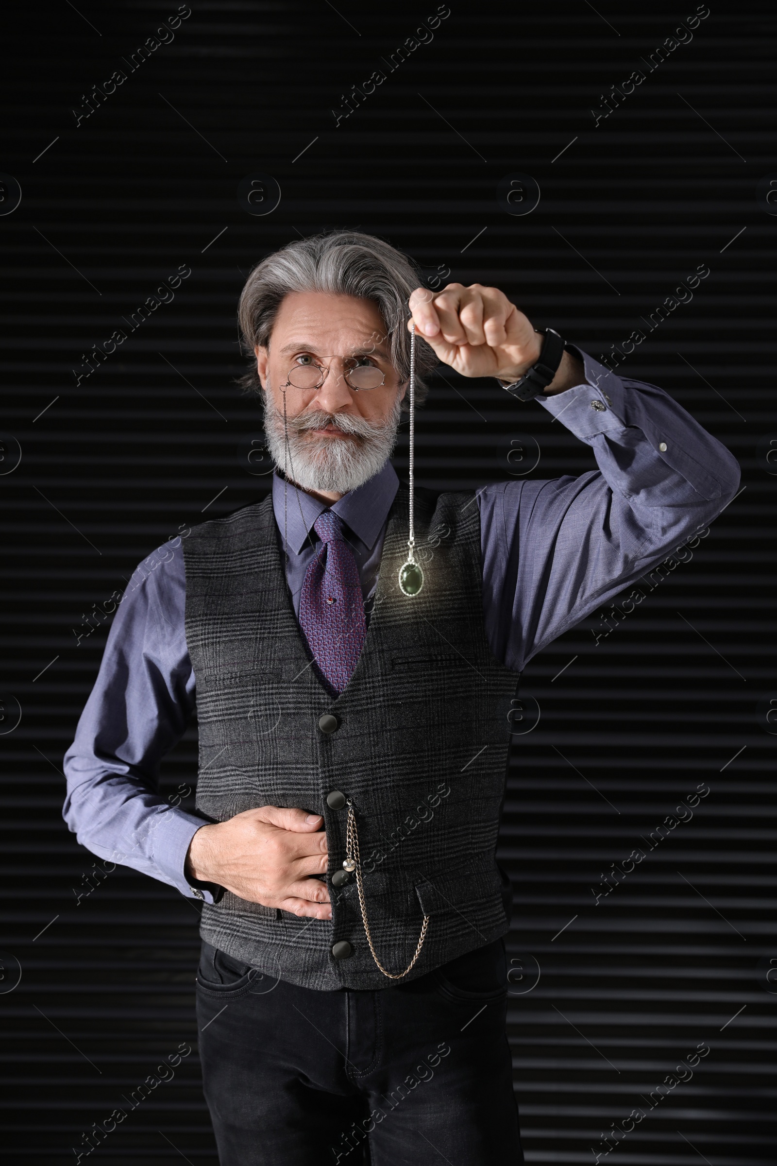 Photo of Psychotherapist with pendulum on black background. Hypnotherapy session