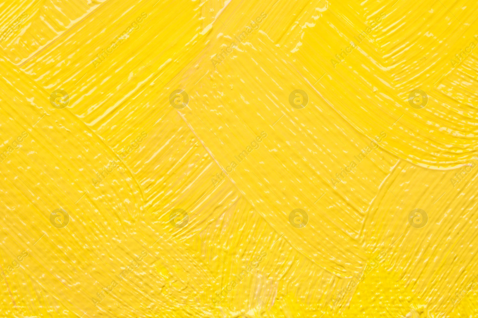 Photo of Beautiful strokes of yellow oil paint as background, closeup