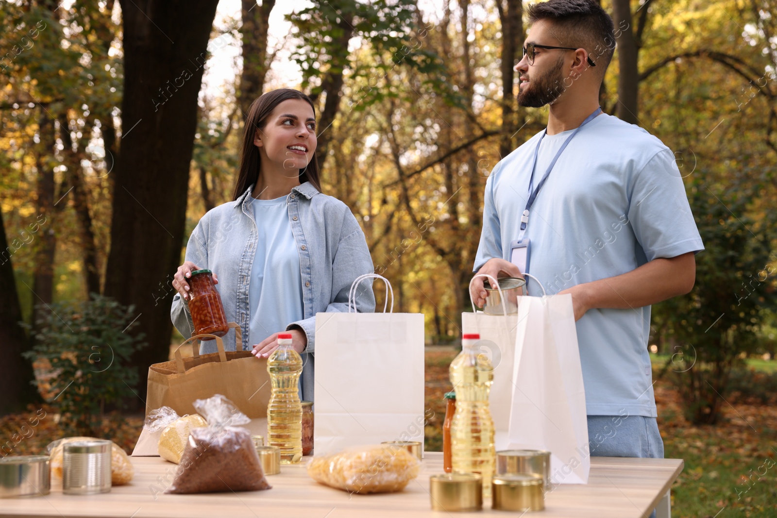 Photo of Volunteers packing food products at table in park