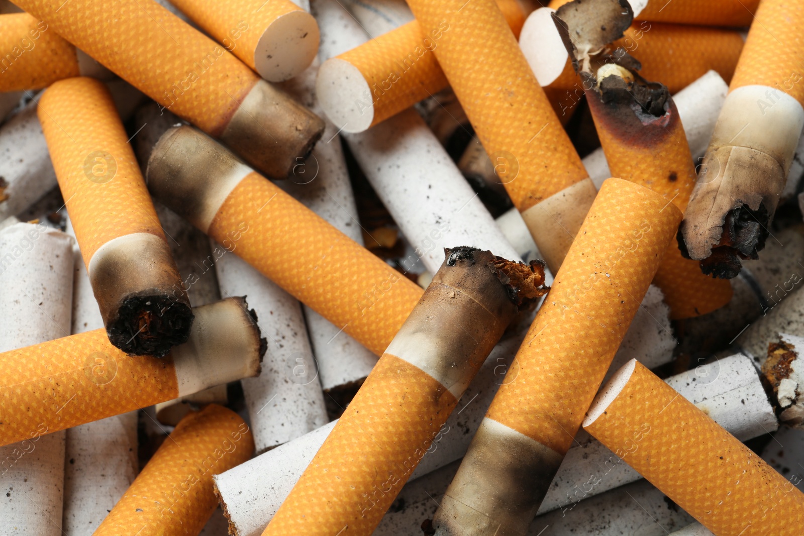 Photo of Pile of cigarette stubs as background, closeup view