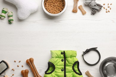 Photo of Flat lay composition with dog clothes, food and accessories on white wooden table. Space for text