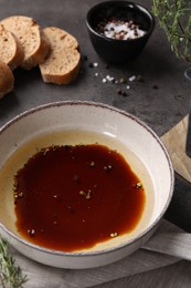 Bowl of balsamic vinegar with oil, spices and bread on dark grey table