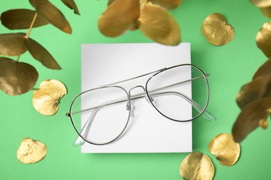 Stylish presentation of glasses on green background, flat lay