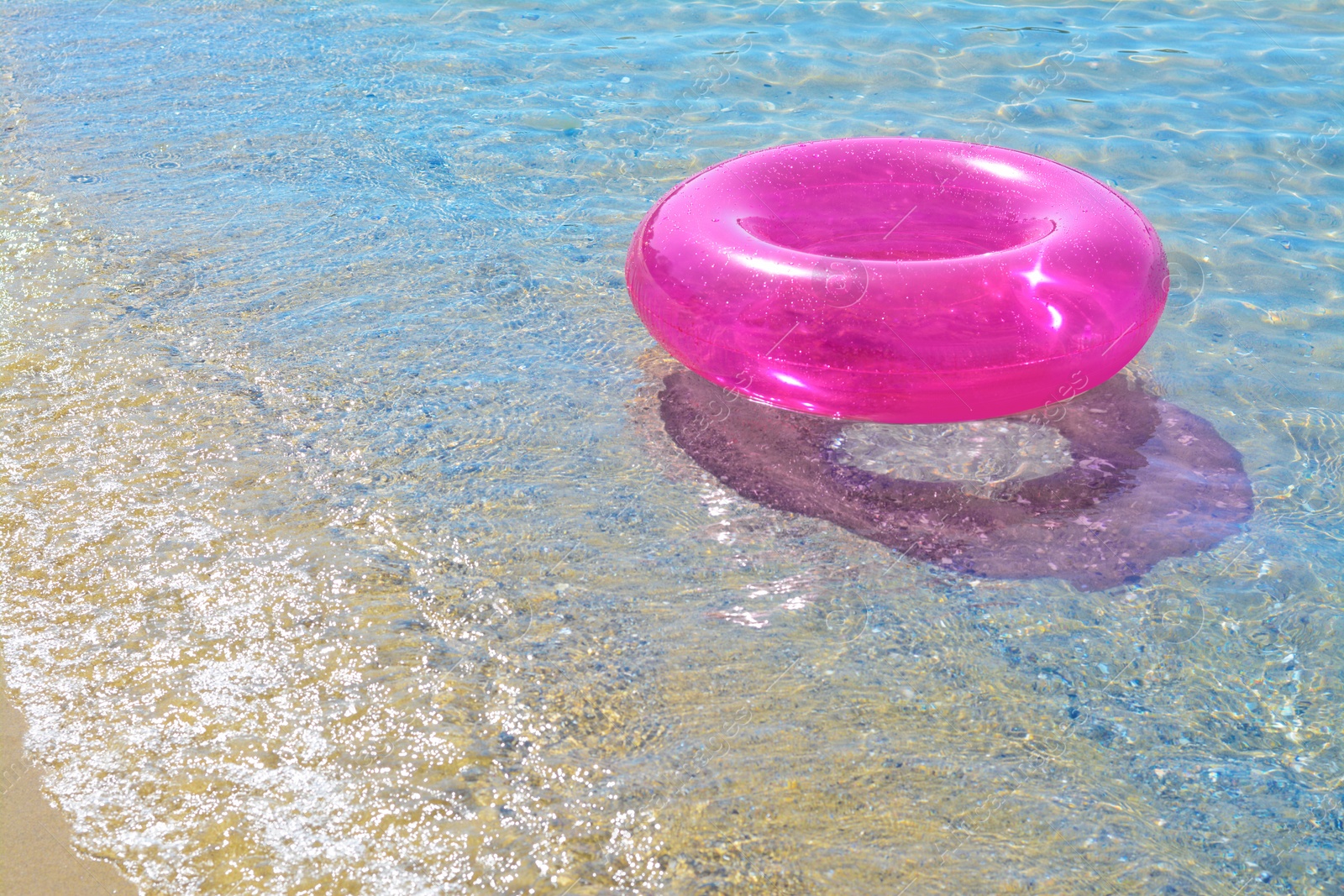 Photo of Bright inflatable ring on sandy beach near sea. Space for text