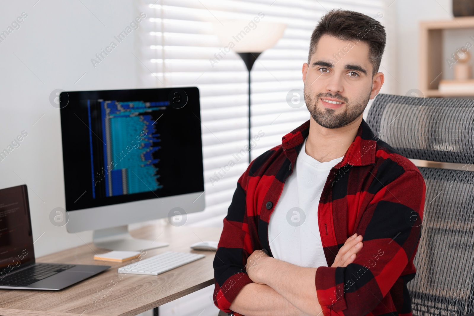 Photo of Happy young programmer working at desk in office