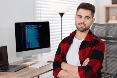 Happy young programmer working at desk in office