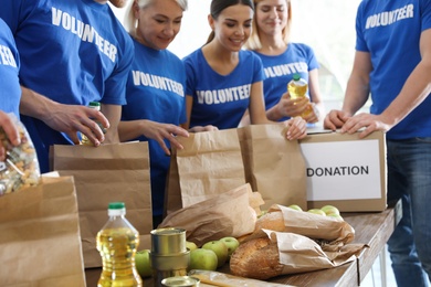 Team of volunteers collecting food donations at table, closeup