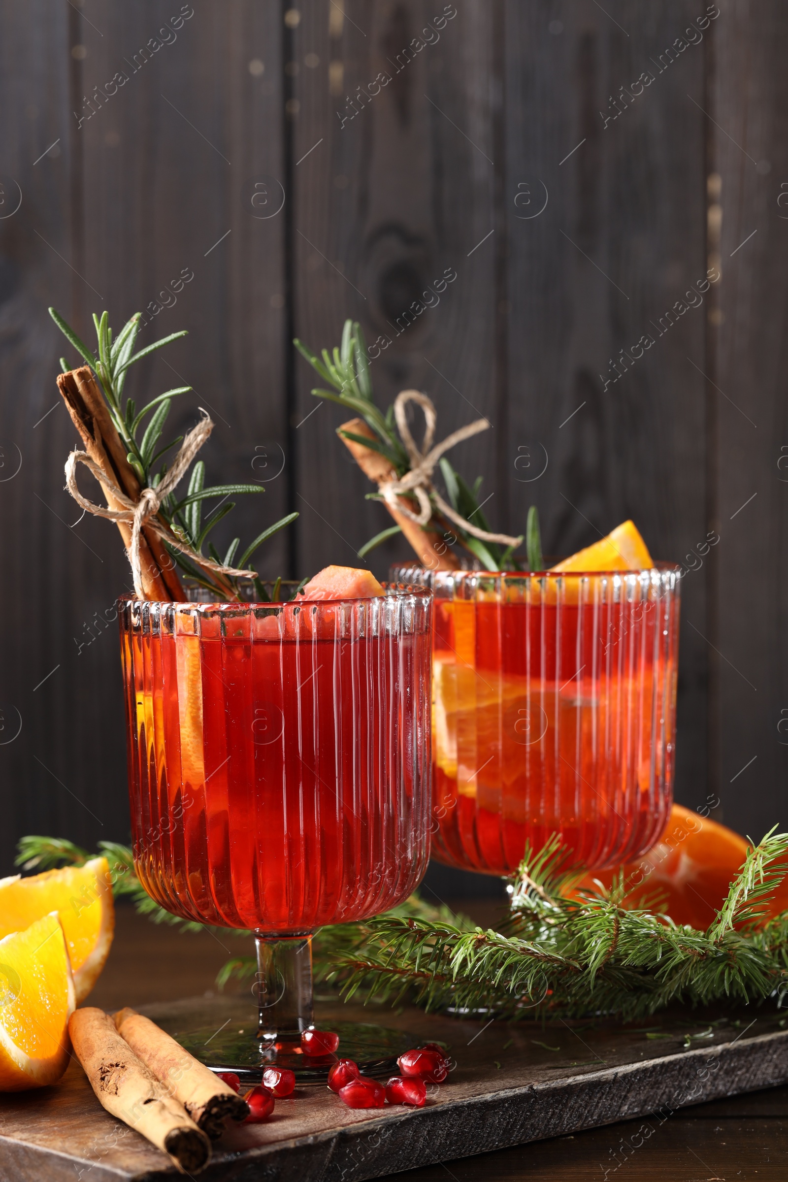 Photo of Christmas Sangria cocktail in glasses, ingredients and fir tree branches on wooden table, closeup