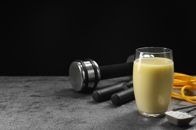 Photo of Tasty shake, sports equipment and powder on grey table against black background, space for text. Weight loss