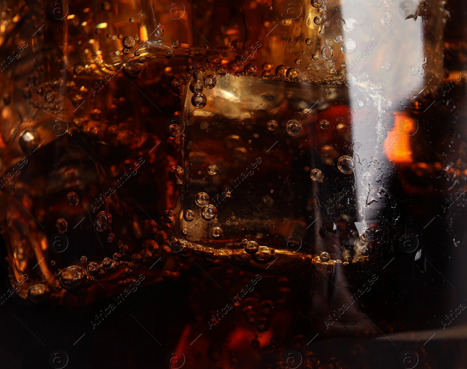 Photo of Glass of refreshing soda drink with ice cubes as background, closeup