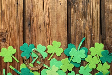 Photo of Flat lay composition with clover leaves and horseshoe on wooden background, space for text. St. Patrick's day