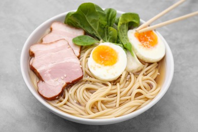 Photo of Delicious ramen with meat on light grey table, closeup. Noodle soup