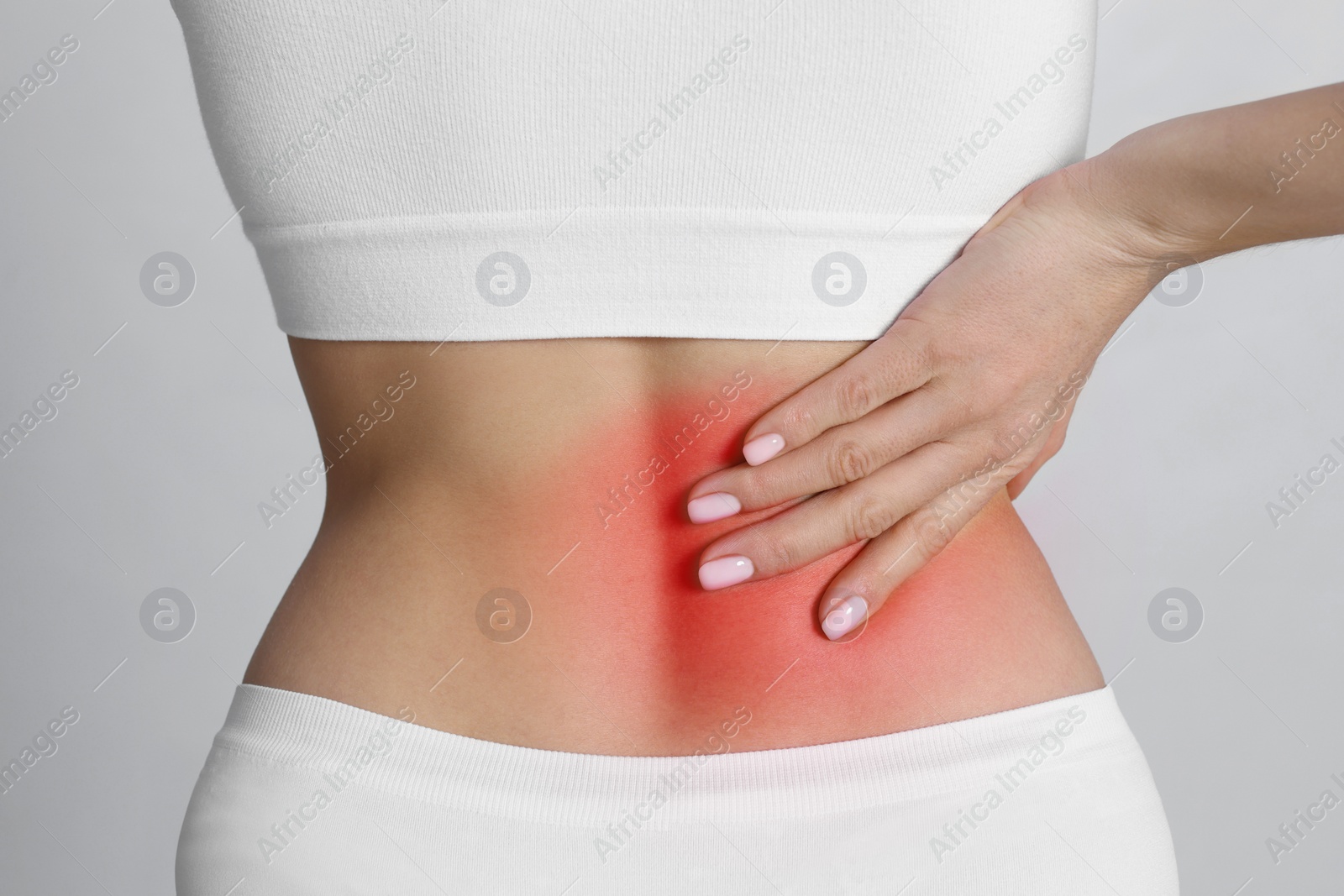 Image of Woman suffering from pain in back on light background, closeup