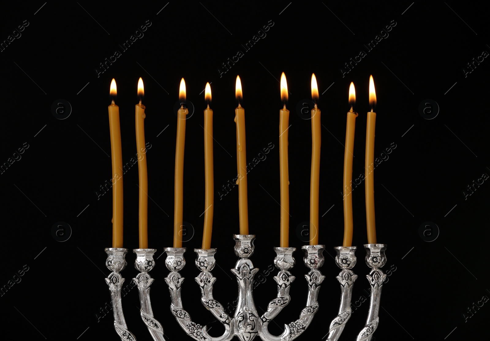 Photo of Silver menorah with burning candles against black background. Hanukkah celebration