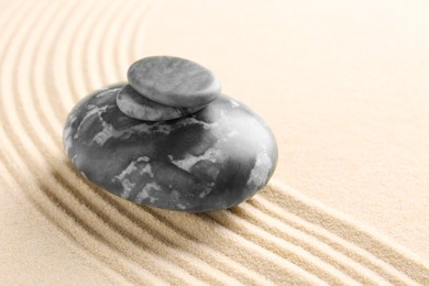 Photo of Zen garden stones on beige sand with pattern. Space for text