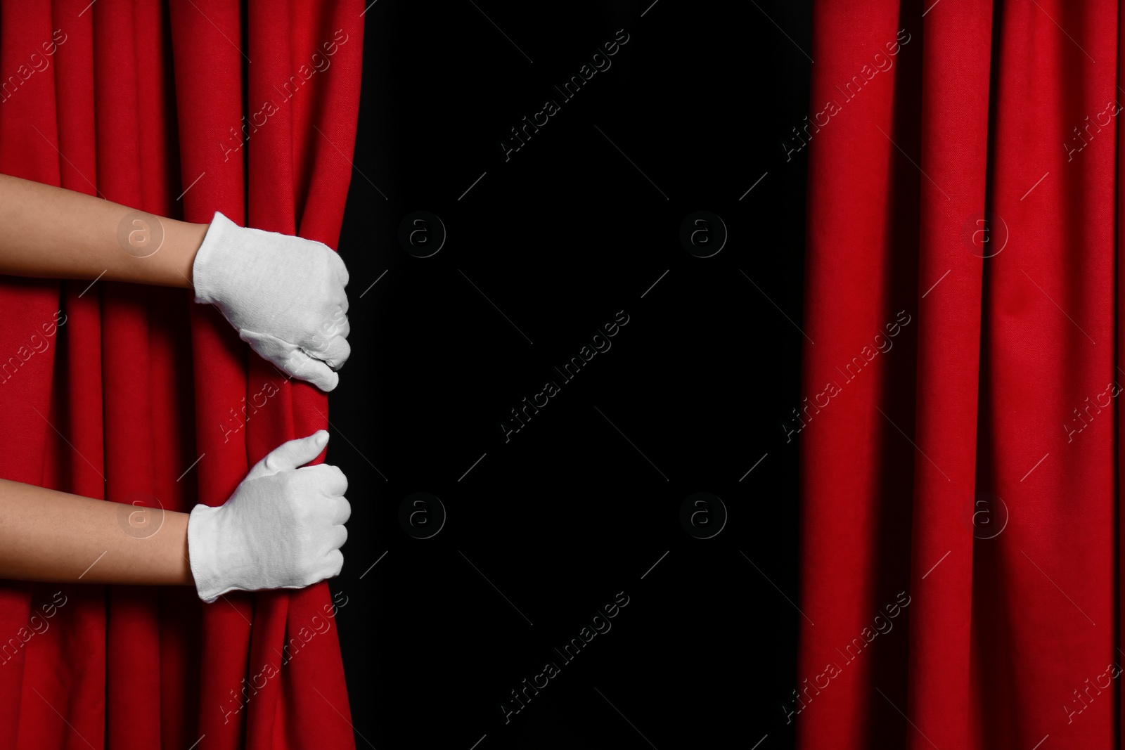 Photo of Woman opening red front curtains on black background, closeup. Space for text